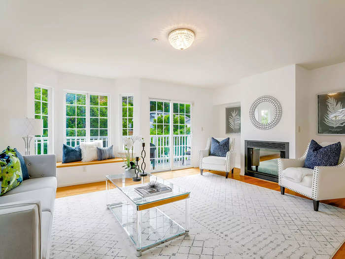 The living room is fitted with expansive bay windows that open to a balcony.