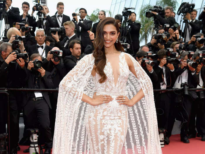 Deepika Padukone attended the festival in a sheer white gown with dramatic floral accents and a matching cape.