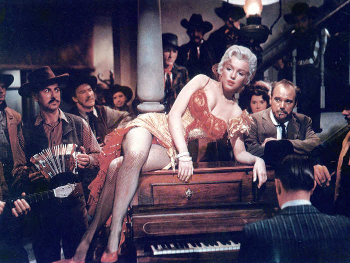 Monroe was always styled in more luxurious looks onscreen, such as her 1950 "River of No Return" yellow silk gown with a high slit, red chest embroidery, and a matching underskirt.