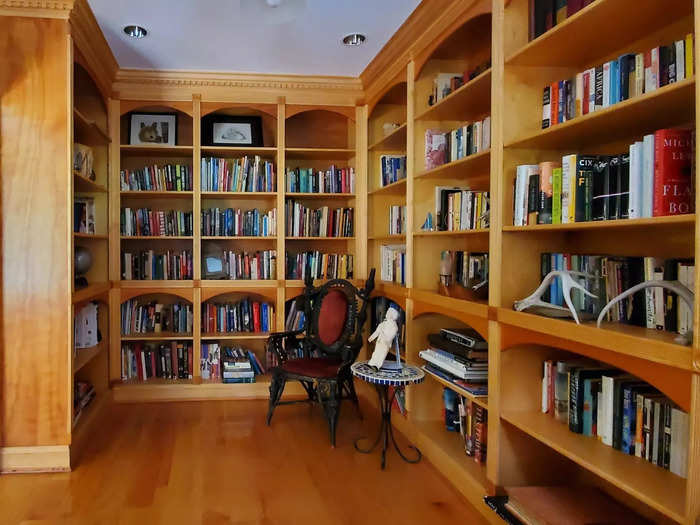 The library is next to the living room, with full-length, built-in shelving.