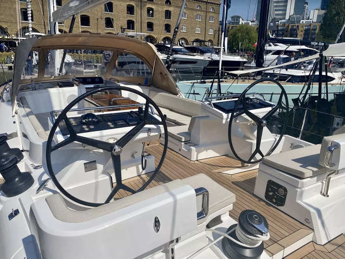 The main deck features two steering wheels facing the outdoor entertainment area with a folding table.