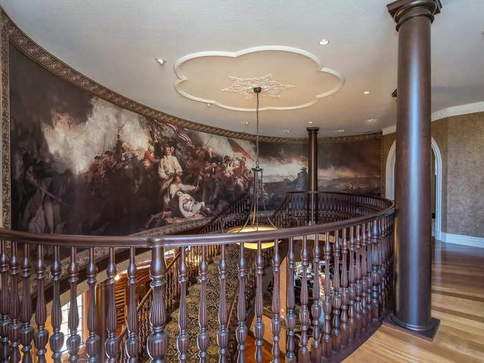 A floating staircase leads from the main entrance to the second floor. At the top of the stairs, a reproduction of a revolutionary war painting covers an entire wall.