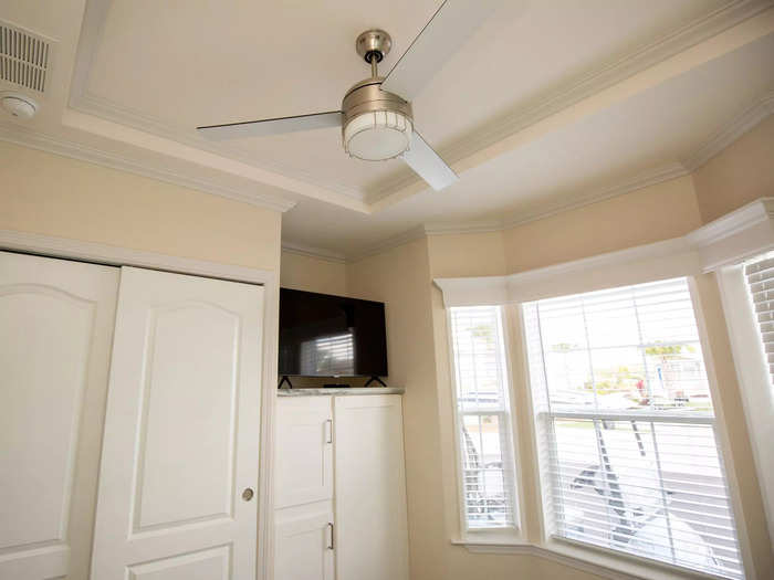 … a ceiling fan, a television, and large windows with sweeping views of the road and adjacent RVs.