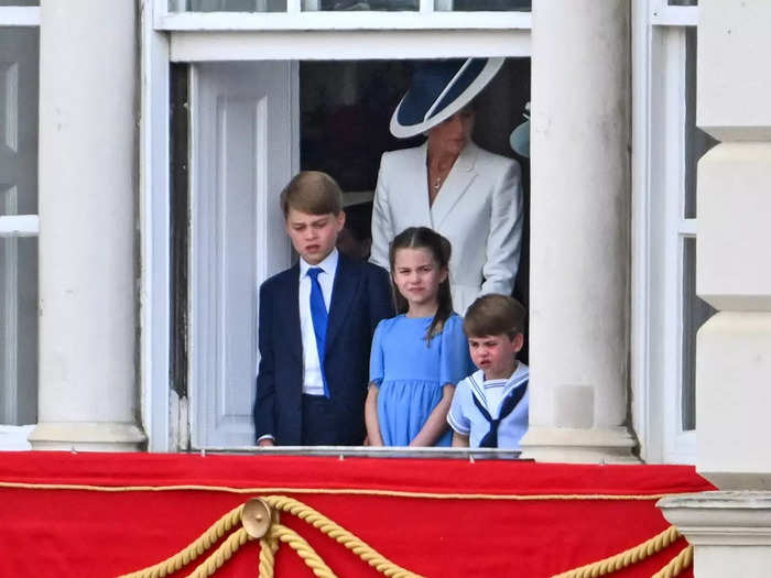 Photographers captured him frowning from a window in Buckingham Palace as he stood next to his siblings.