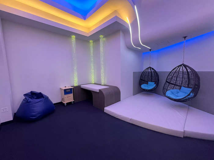 The room has calm lighting and hanging chairs…