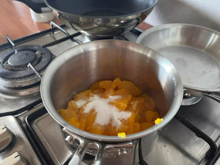 To make the mandarin coulis, take one of your cans of fruit and drain it fully, before adding it to a saucepan with the caster sugar.