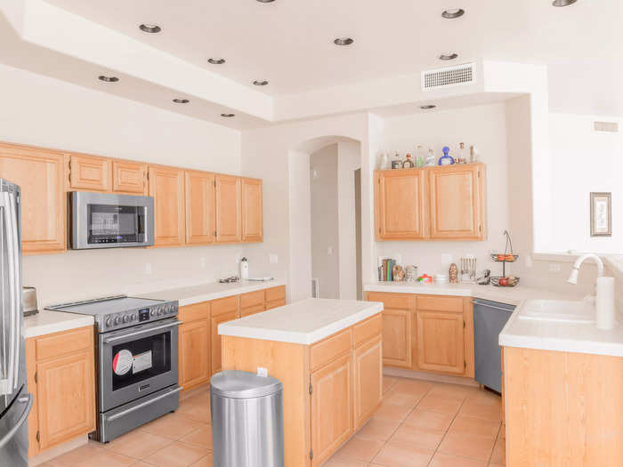 Across from the golf course, the kitchen is bright with white countertops and walls and stainless steel appliances.