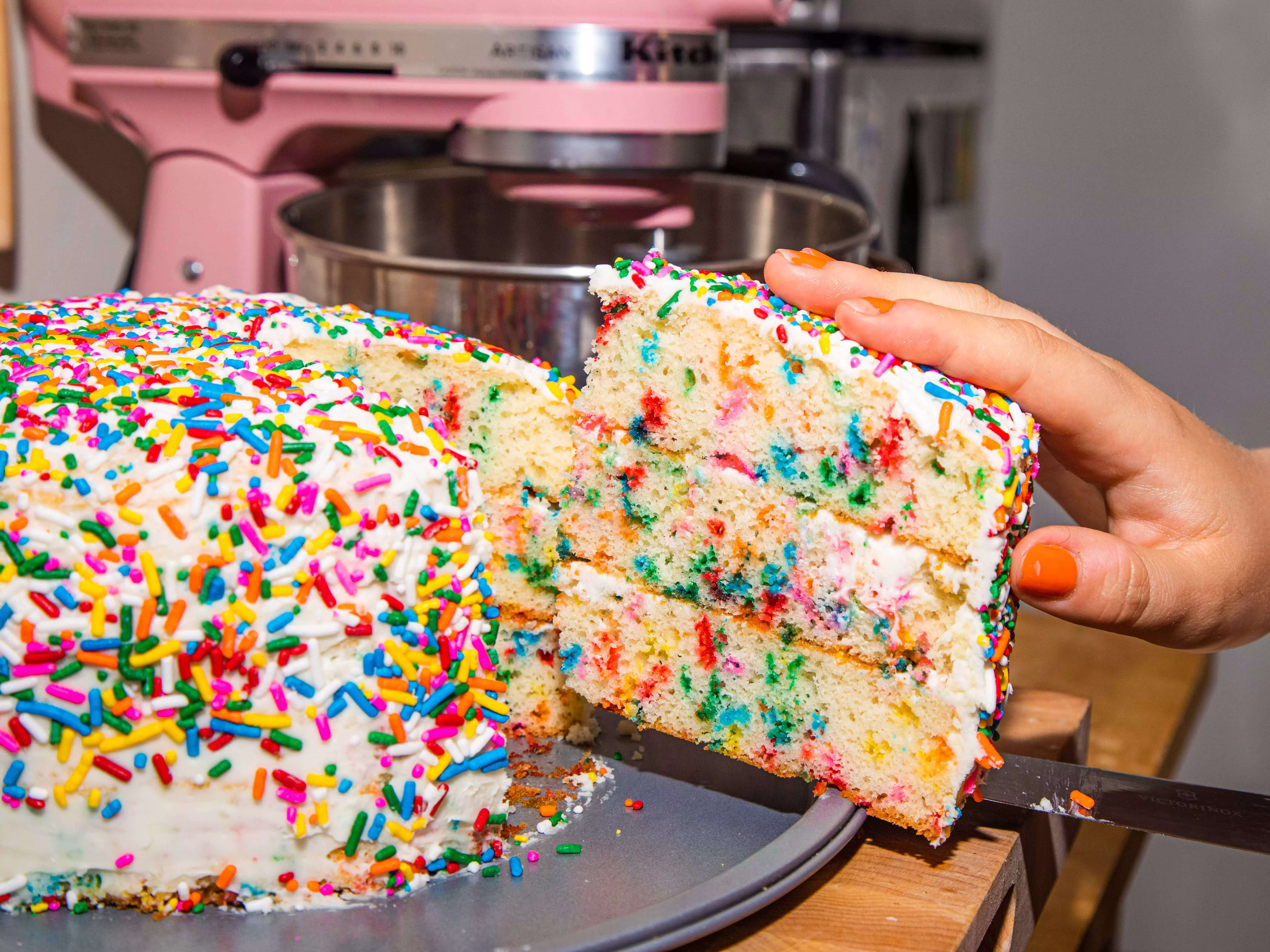 a hand pulling out a slice of funfetti cake