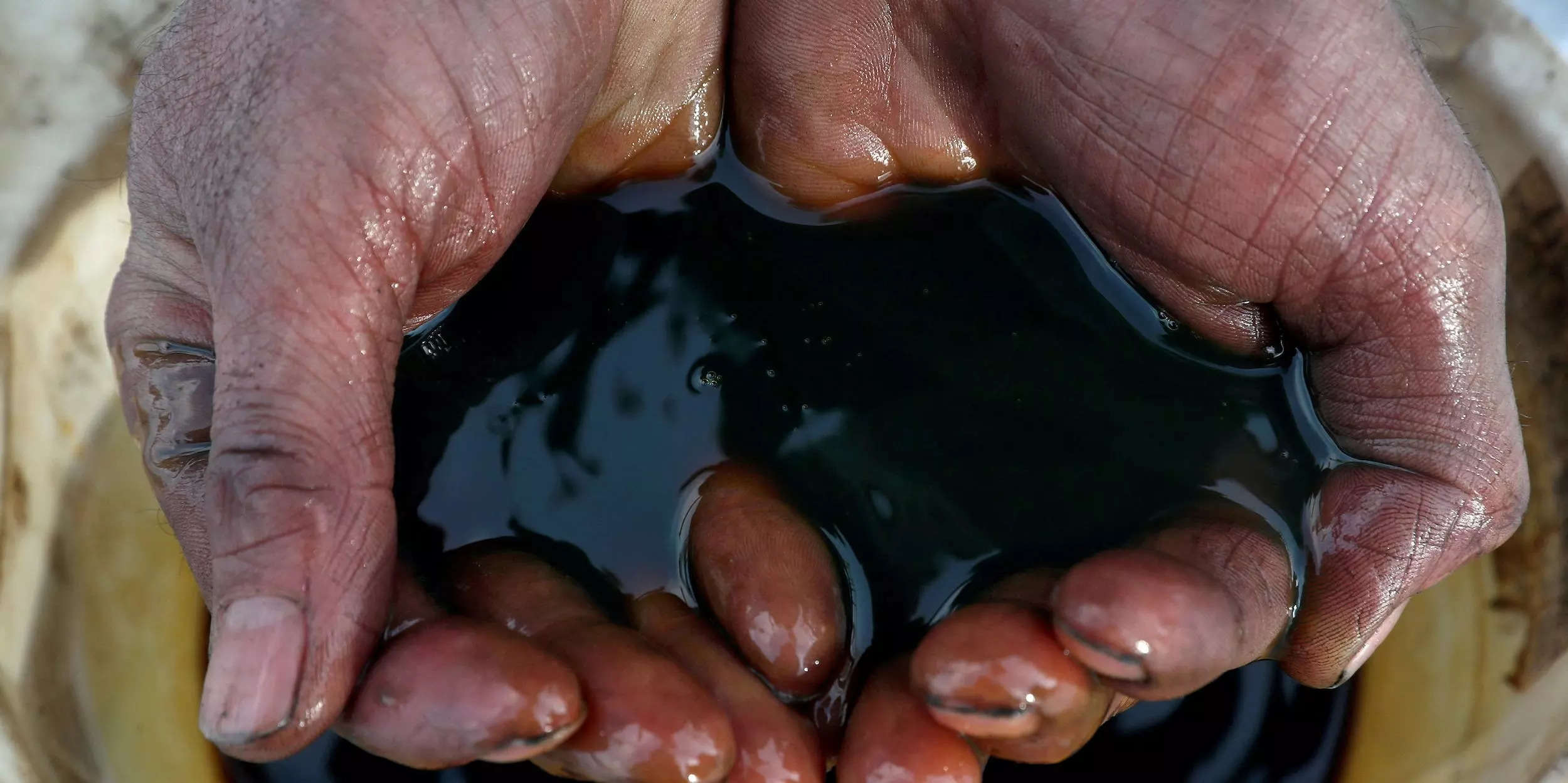 pair of hands cupped holding crude oil