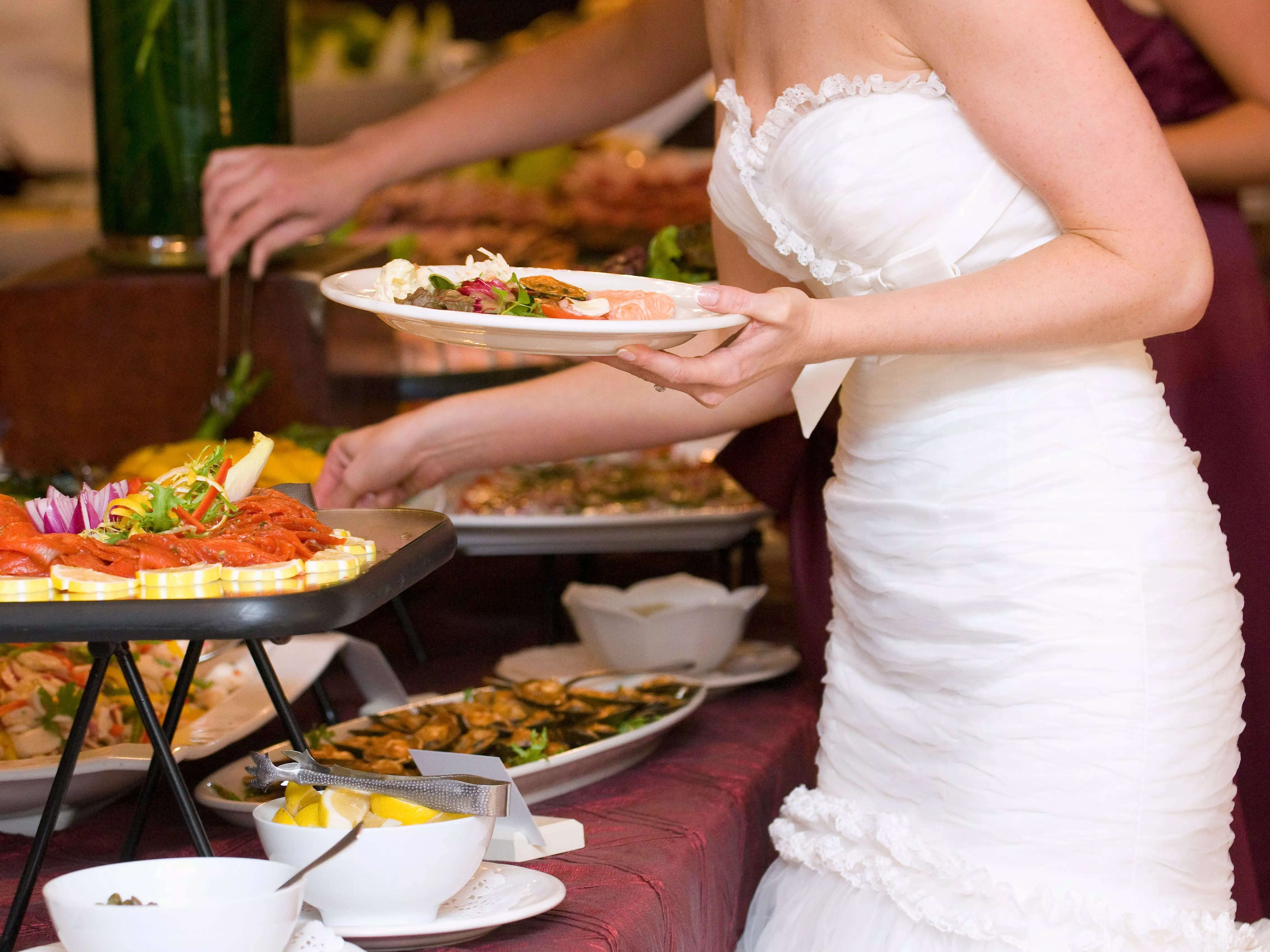 Bride in white dress serving herself some food at her wedding