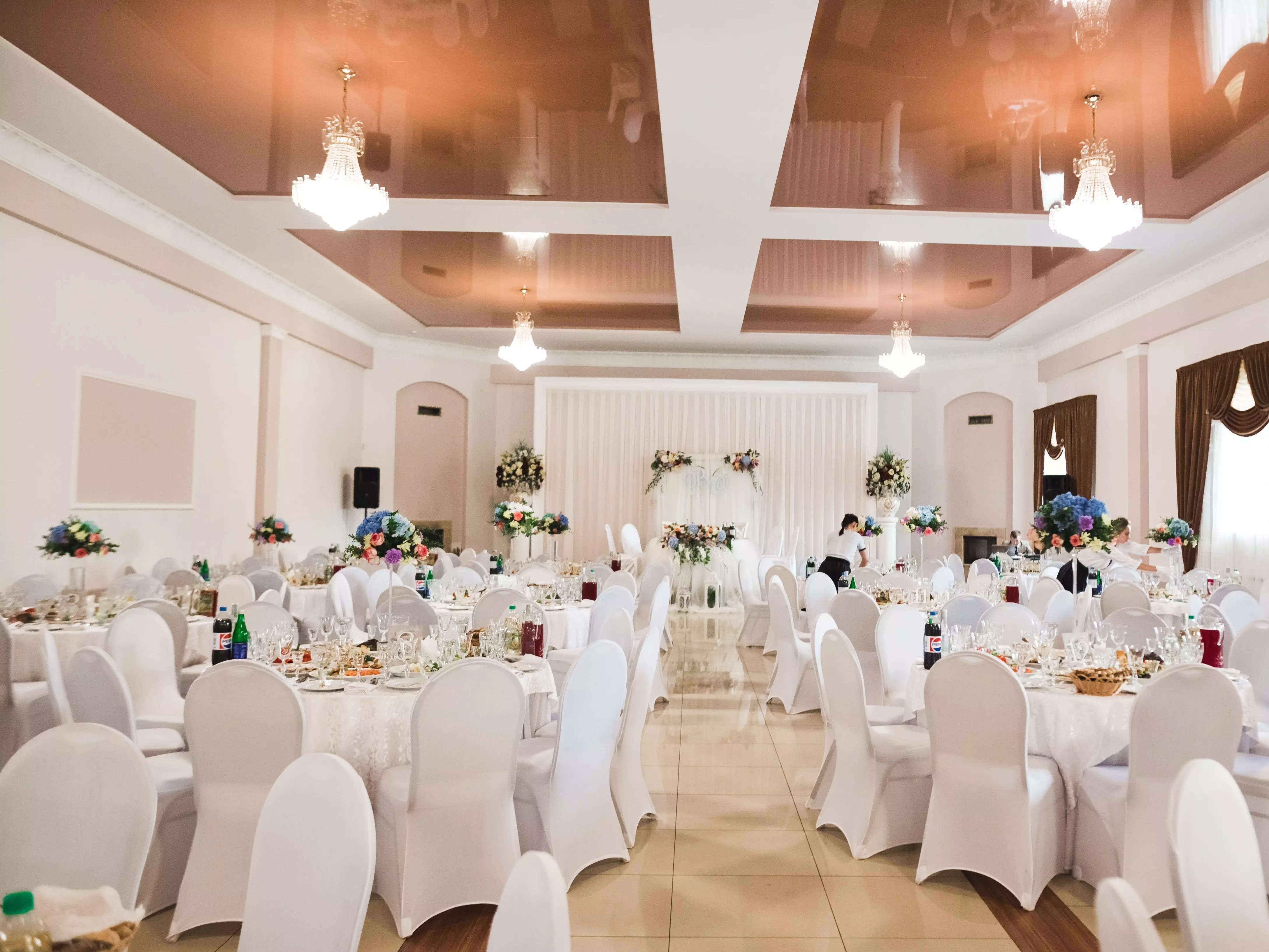 a wedding venue banquet hall with white chairs and tables set up