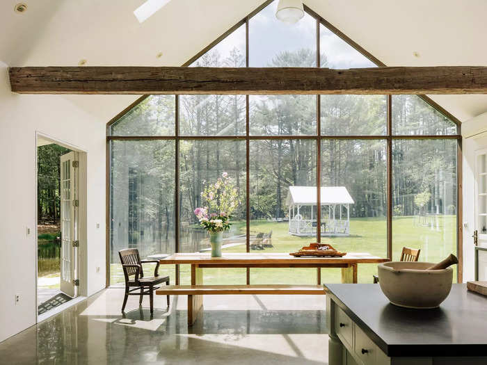 The dining area is flanked by a towering wall of glass and steel that overlooks the lawn.