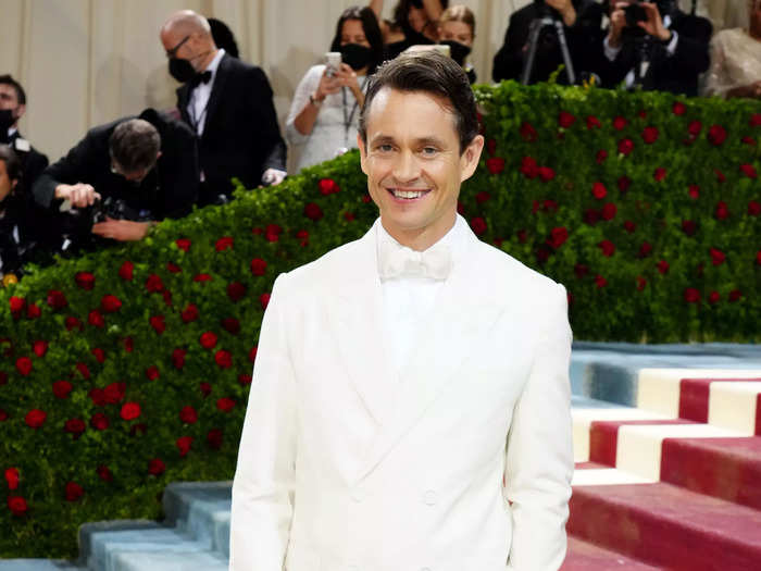 In real life, Hugh Dancy parts his shorter hair to one side and goes for monochromatic outfits, like this all-white number he wore to the Met Gala.