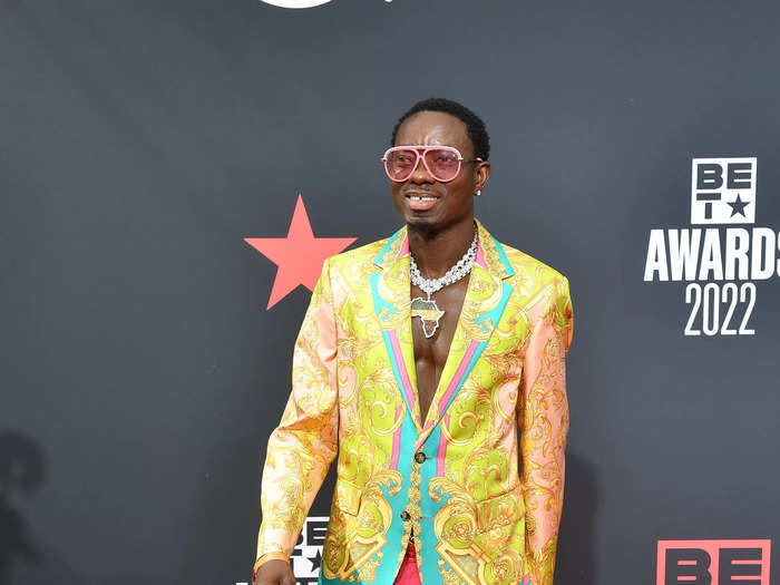 Michael Blackson clashed colors in a multi-colored jacquard blazer with deep-pink skinny pants and yellow loafers.