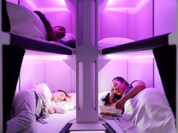 People rest on bunk beds, bathed in purple light