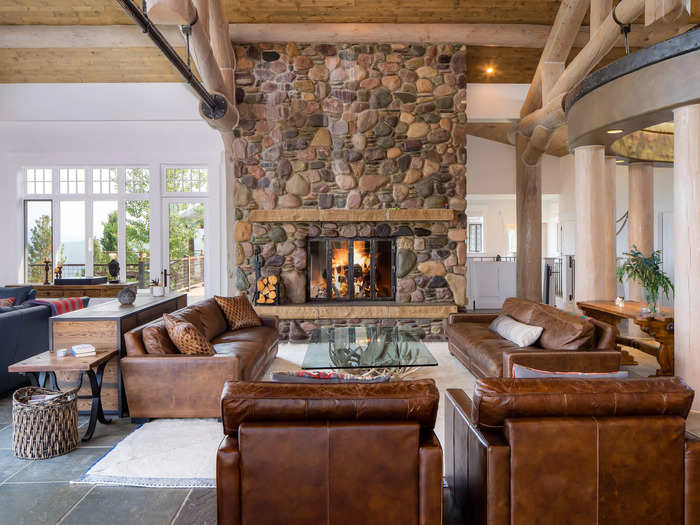 A grand stone fireplace forms the centerpiece of the living area in the main home. Made from river rock, the floor-to-ceiling fireplace takes up an entire wall.