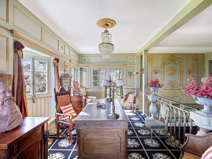 A large wooden desk forms the centerpiece of the study, which is located on a mezzanine floor that overlooks the main living area.