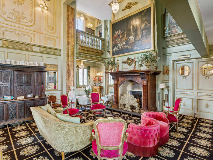 The main living area has high ceilings, intricate wall moldings, and a giant wood fireplace mantle.