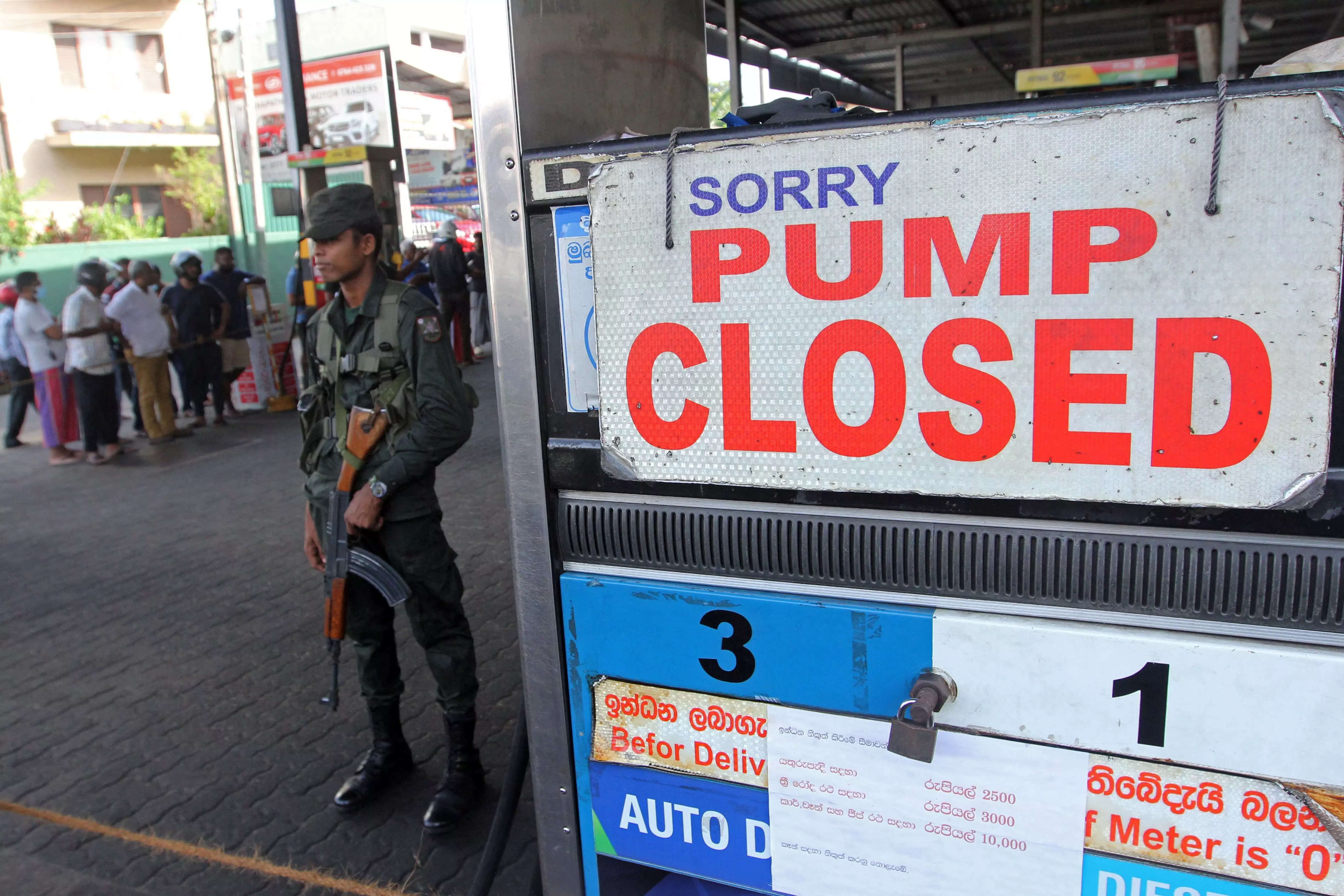 A member of Sri Lankan security personnel stands guard outside a fuel station that ran out of gasoline in Colombo on June 27, 2022.