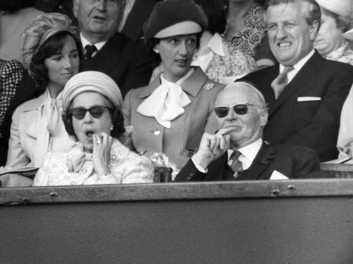 The Queen appears to wipe the corner of her lips while seated in the Royal Box at Wimbledon in 1977.