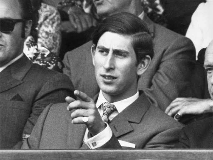 Prince Charles, then roughly 22, points his finger toward the tennis action at Wimbledon in 1970.