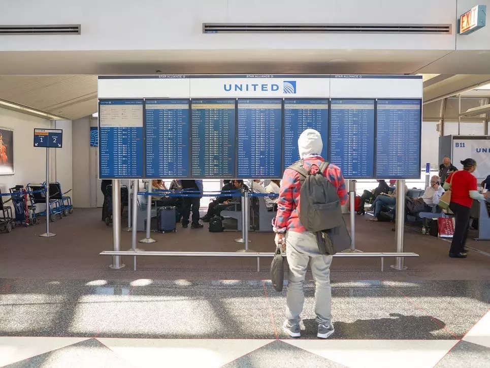 Passengers stands in front of United departure and arrival board