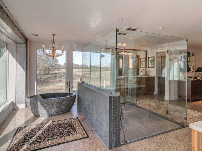 The ensuite master bathroom features a glass-enclosed double shower and a hand-chiseled stone bathtub.