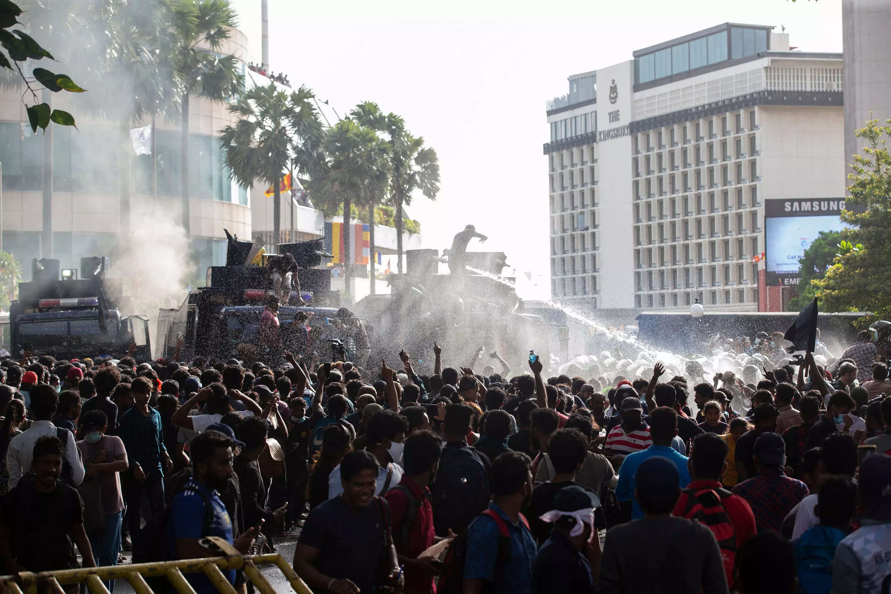 Protesters on the street with a water cannon behind them.