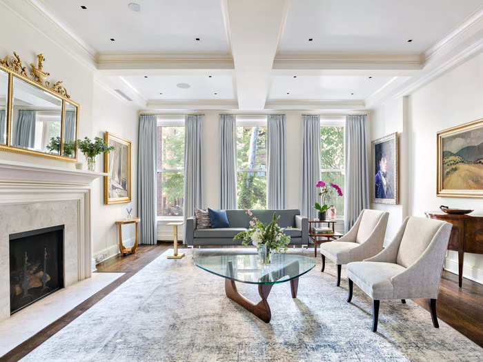 The formal living room has a fireplace and large, identical windows that offer views of New York City.