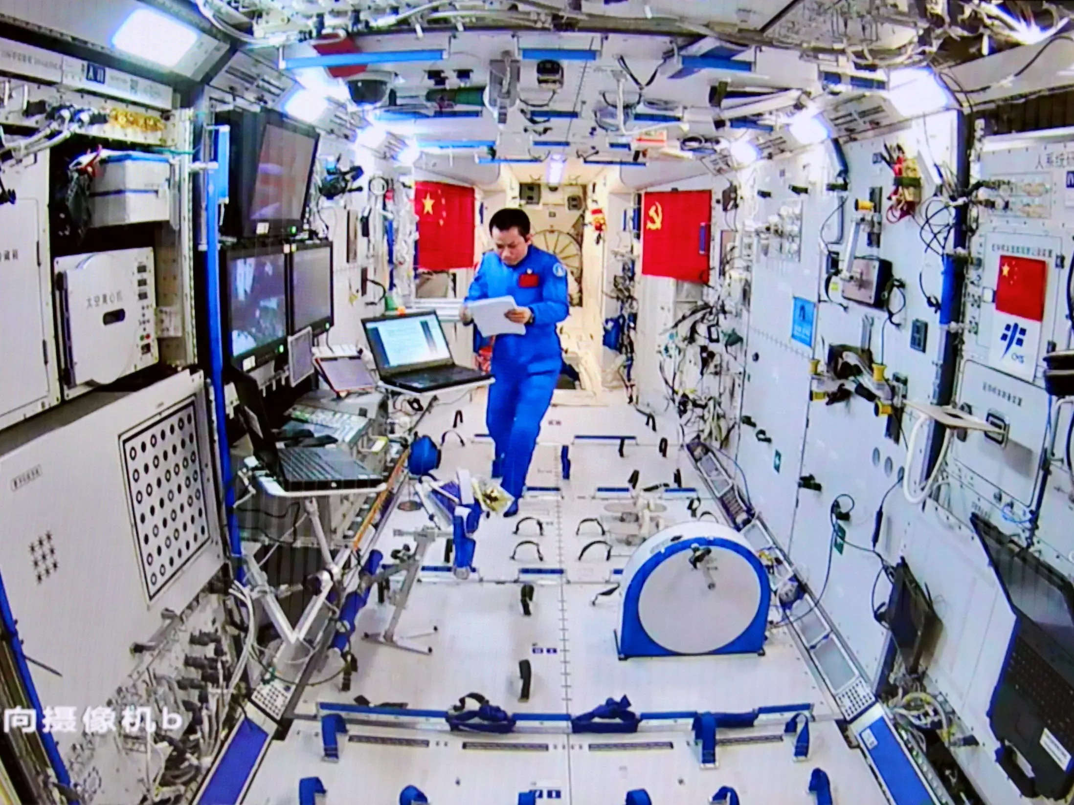 astronaut taikonaut in chinese space station looking at papers wearing blue jumpsuit