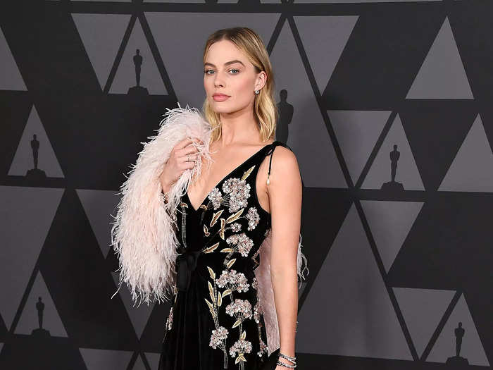 Margot Robbie attended the Governors Awards in 2017 wearing a black velvet dress with floral embroidery and a pink shrug.