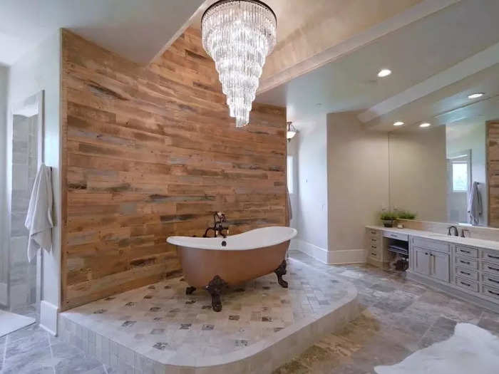 The bathroom off the primary bedroom offers a free-standing tub and chandelier.