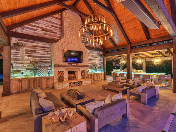 The pool area also has a rustic TV area and an outdoor kitchen.