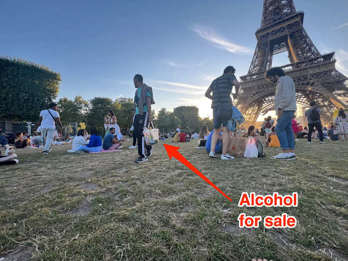 People walk around offering wine and beer for sale at the Eiffel Tower like it