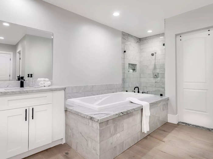 The main bathroom has multiple vanities and ample cabinet space, as well as a soaking tub.