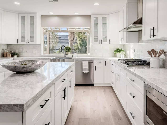 In addition to a large island, the kitchen has marble countertops, stainless steel appliances, and glass cabinets that add to the modern feel of the home.