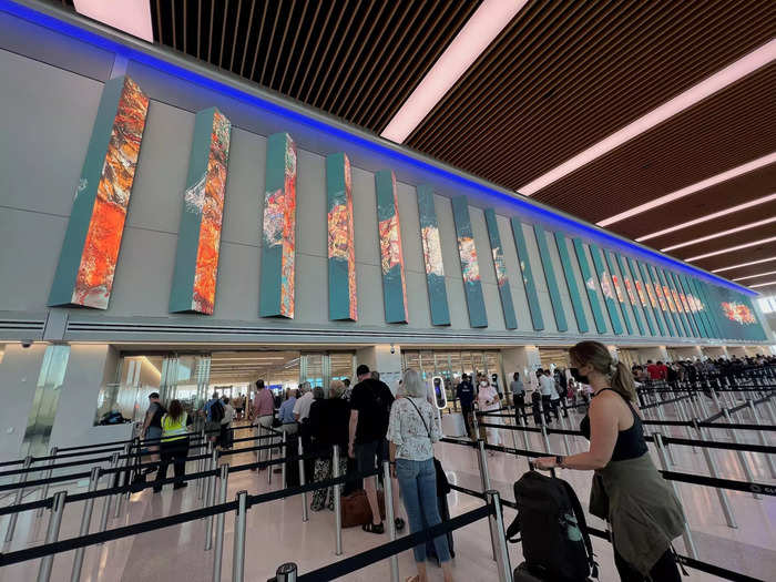 To get to security, travelers will take the escalator up to the third level. Here, there is a giant digital art installation created by ESI Design, an NBBJ Studio.