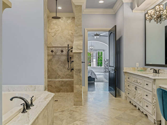 There are nine bathrooms in the home. The master bathroom has a shower, a bathtub, and a large vanity.