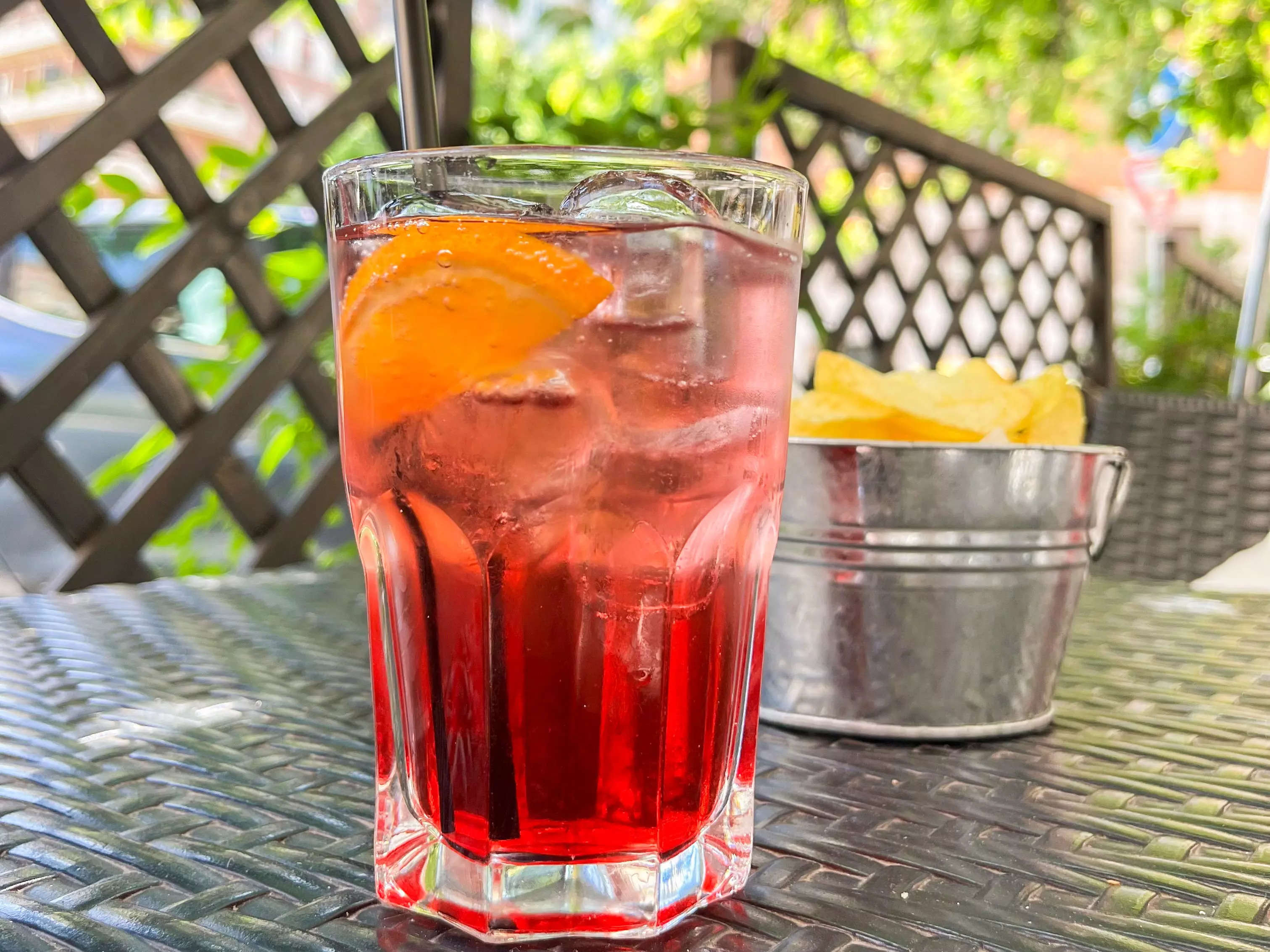A Campari Spritz on a table with potato chips.
