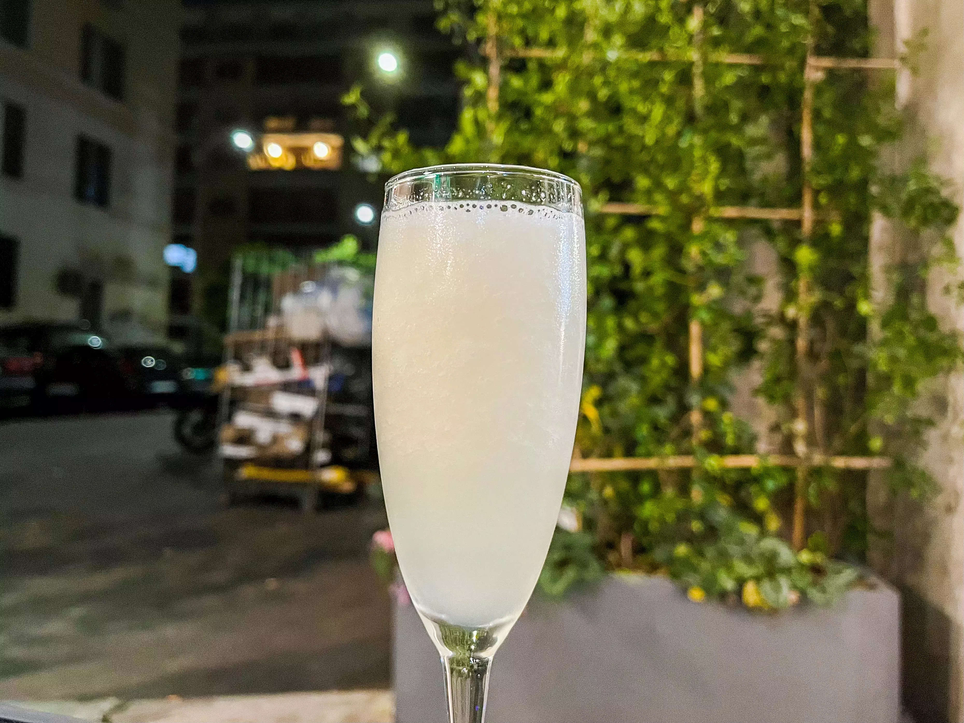 A Sgroppino cocktail on a table in front of a vine covered trellis.