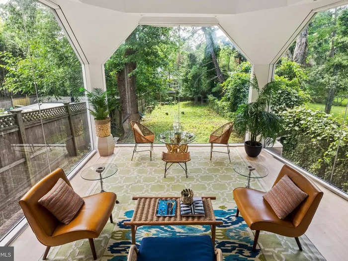 A sunroom at the back of the house has glass walls that overlook the backyard.