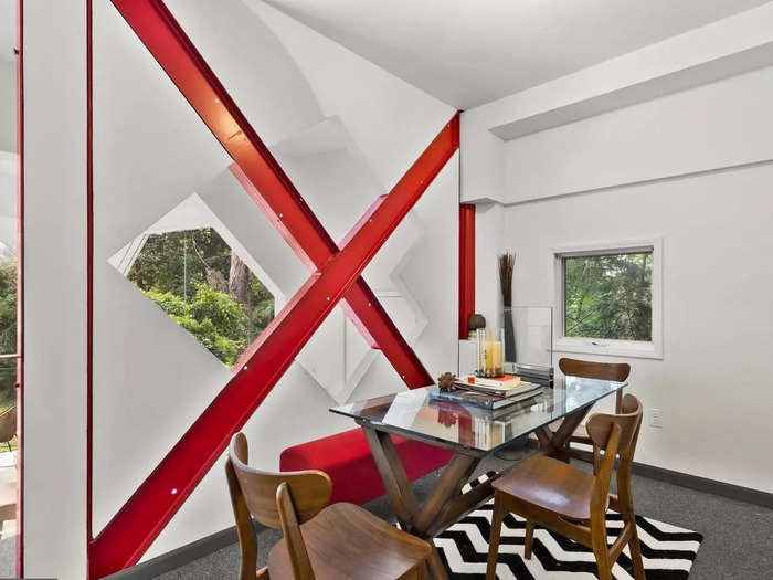 Instead of hiding the support beams, Darvish chose to incorporate them into the interior design: The red "X" is an exposed metal beam that he used as a bookshelf.