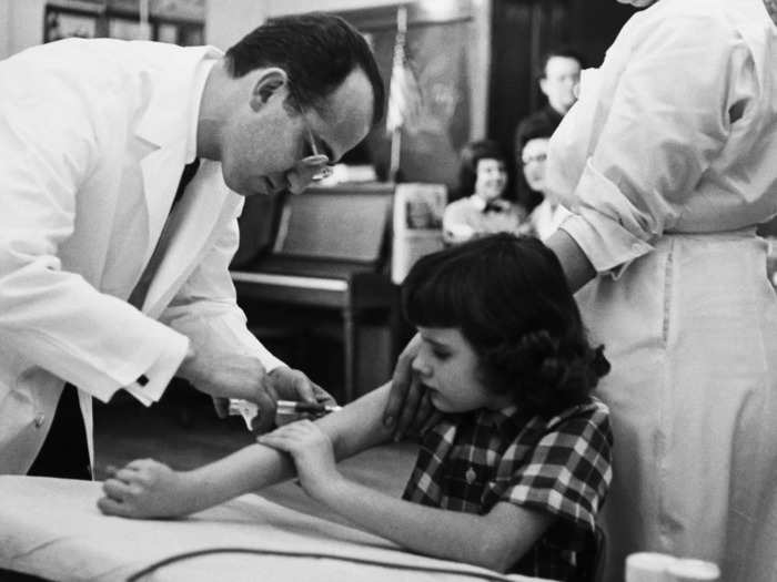 1954: Dr. Jonas Salk gives a shot of the polio vaccine to a girl during test trials.