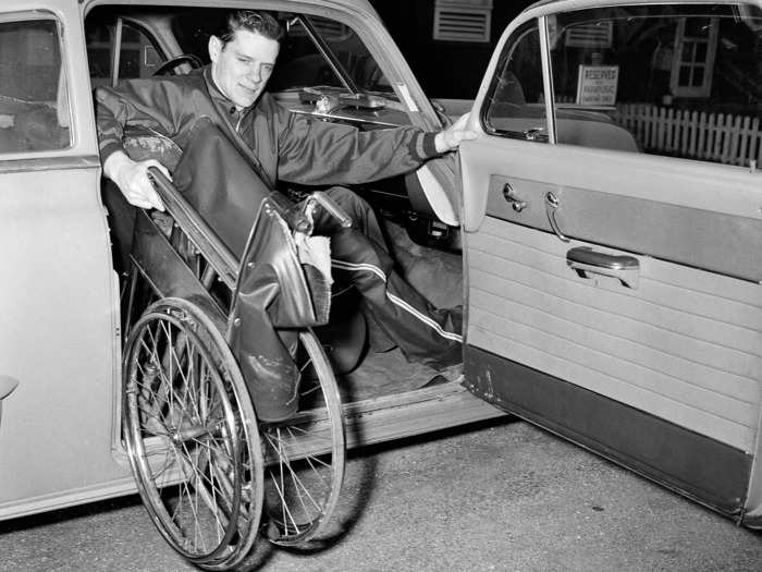 March 7, 1952: Jack Chase, a student at the University of Illinois, lifts his wheelchair into his car after contracting polio while serving in Korea in 1946.