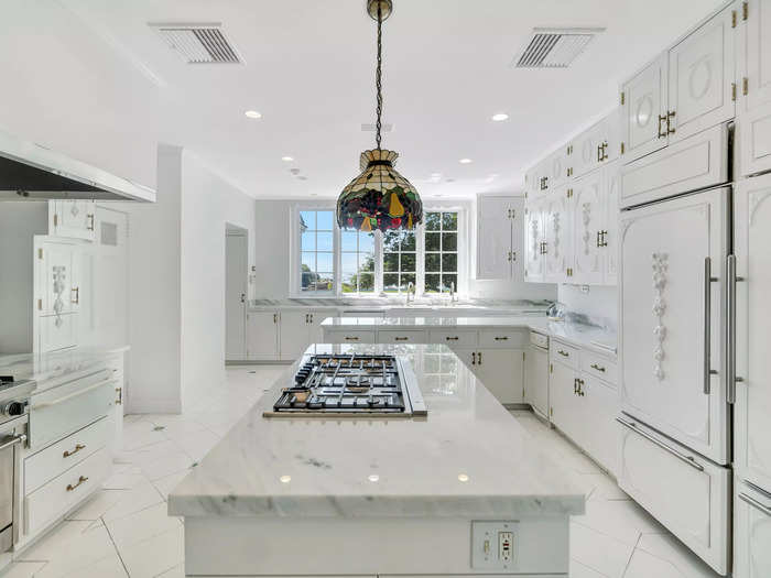 The kitchen is extremely white, with new appliances and marble countertops.