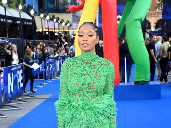 Attending the UK premiere of "NOPE," Keke Palmer wore a bright green sheer lace maxi dress with a feather belt.