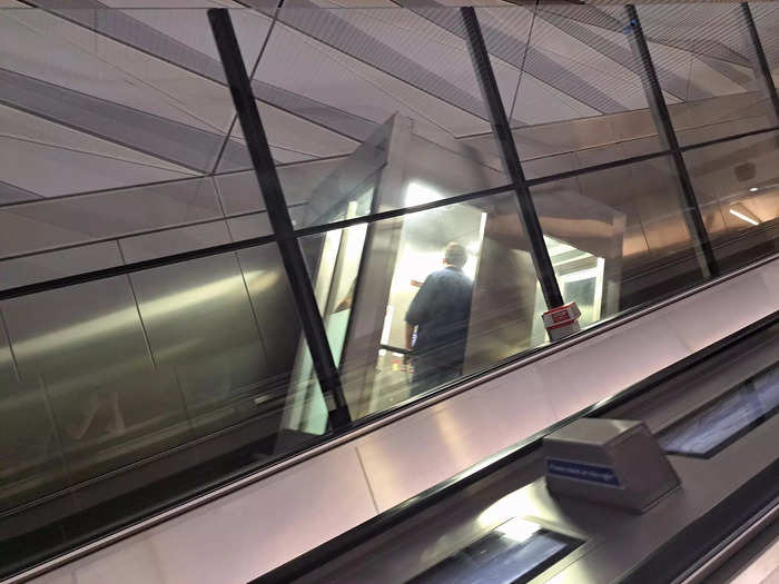 The shaft and the elevator car are clearly visible from the escalator.