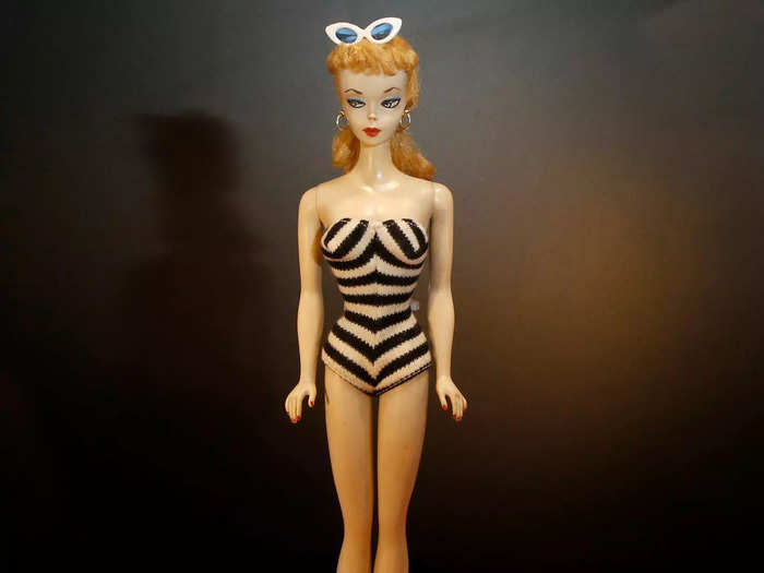 The first Barbie doll in 1959 wore a striped swimsuit, red lipstick, and had a blonde ponytail.