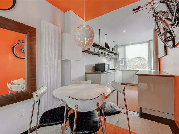 The owner lives on the top two floors, which has an orange and white aesthetic. They even managed to fit a bike into the kitchen.