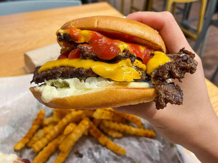 The Beast Style has two smashed beef patties, American cheese, pickles, diced white onions, mayonnaise, ketchup, and mustard between a roll.